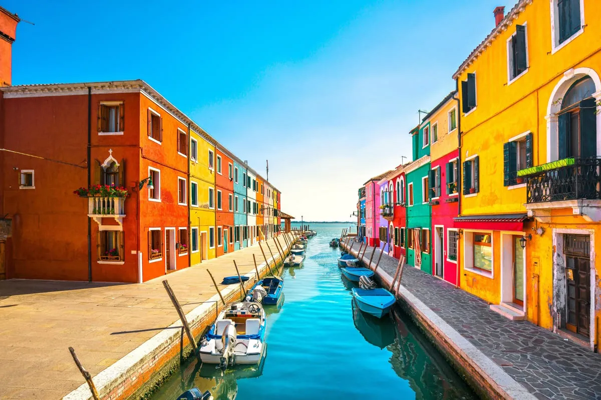 Small group of travellers boarding a private wooden boat in Venice for a Murano and Burano guided tour with glassmaking demonstration, Italy